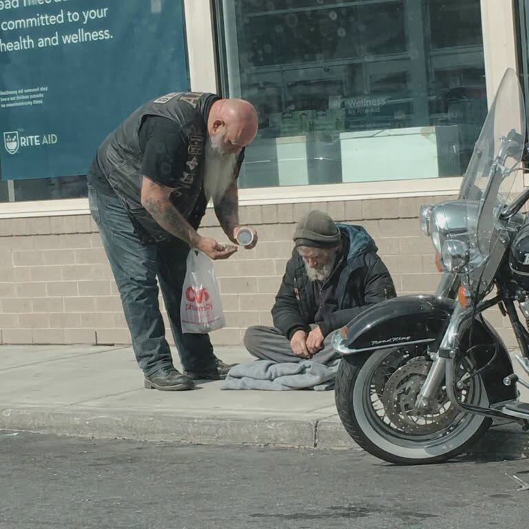 Ich habe einen Motorradfahrer gefilmt, der einem Obdachlosen Geld abnahm und dann hineinging.